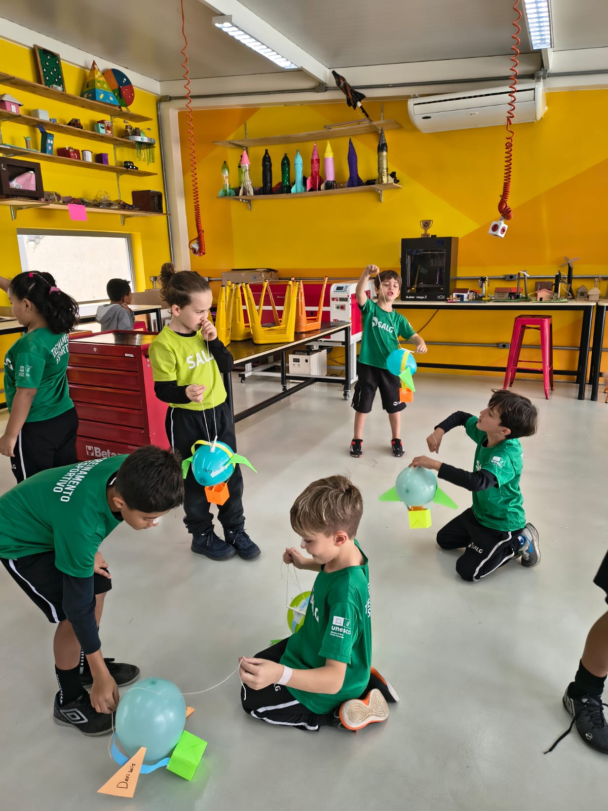Grupo de alunos manuseando foguetes de bexiga no espaço maker durante a aula de Cultura e Inovação